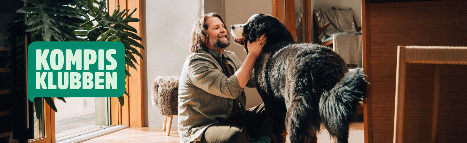 Kompis-klubben Bild p&aring; en glad man som sitter p&aring; golvet och gosar med en hund